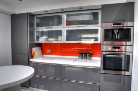 Grey gloss kitchen with orange splashbacks and Corian tops