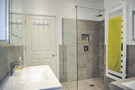 Bathroom installation with grey tiled shower enclosure including niche and wet room base with Kudos shower screen