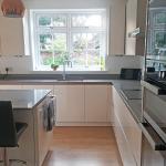 Looking towards the window in a kitchen with glossy magnolia units and grey quartz worktops