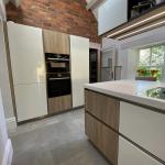 At one end of the kitchen there are tall housings including a fridge freezer, raised ovens and storage
