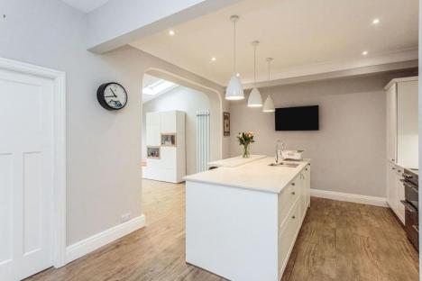 End on view of the kitchen island showing the spacious layout and looking towards the archway to the extension.