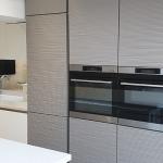 raised ovens installed in tall cabinets with vertical handle trim