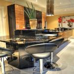 The dining table end of the island showing the different levels of worktops and the high gloss black finished panels beneath the tabletop.