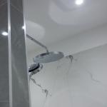 Fixed rain shower and hand shower are plumbed in behind the pillar in the centre of the room