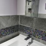 Close up of ensuite basin and mirrored cabinet showing detail of Dune glass mosaic tiles