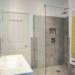 Bathroom installation with grey tiled shower enclosure including niche and wet room base with Kudos shower screen